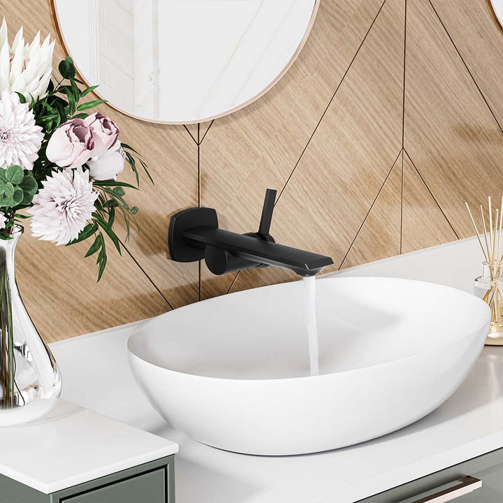 Black wall-mounted faucet flowing water into modern vessel sink