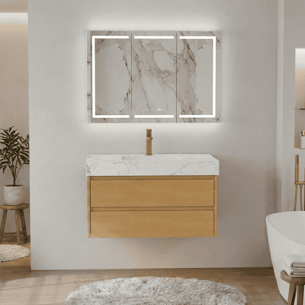 Floating light wood bathroom vanity with two drawers, white marble countertop, brass faucet, and an LED mirror cabinet in a modern bathroom