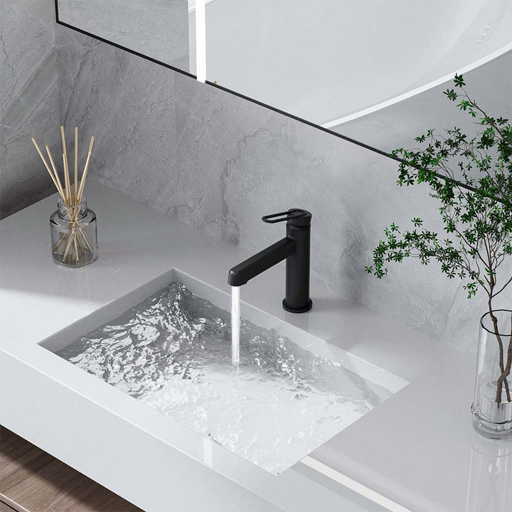 Matte black faucet with running water on white bathroom vanity