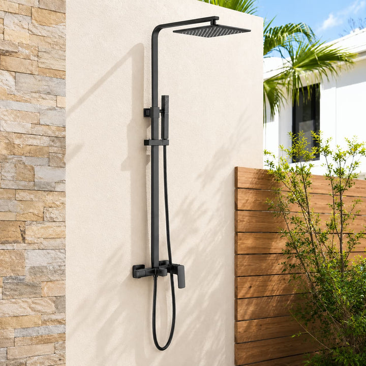 Matte black wall-mounted outdoor shower system with rainfall head and handheld sprayer installed on a modern patio wall