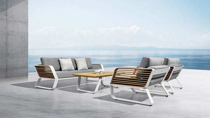 Modern aluminum and wood outdoor sofa set with gray cushions by the ocean view terrace