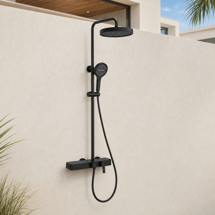 Matte black outdoor shower system with rainfall head and handheld sprayer installed on a modern American patio wall.
