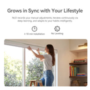 Woman fitting a MODLAND P5 motorized roller shade above a window using mounting brackets.