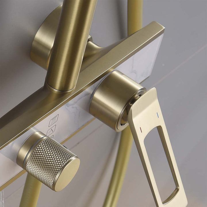 Brushed gold shower handle and temperature control on white panel.