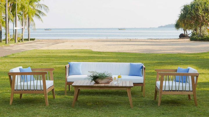 Teak outdoor 5-seat conversation set with white cushions and coffee table on lawn