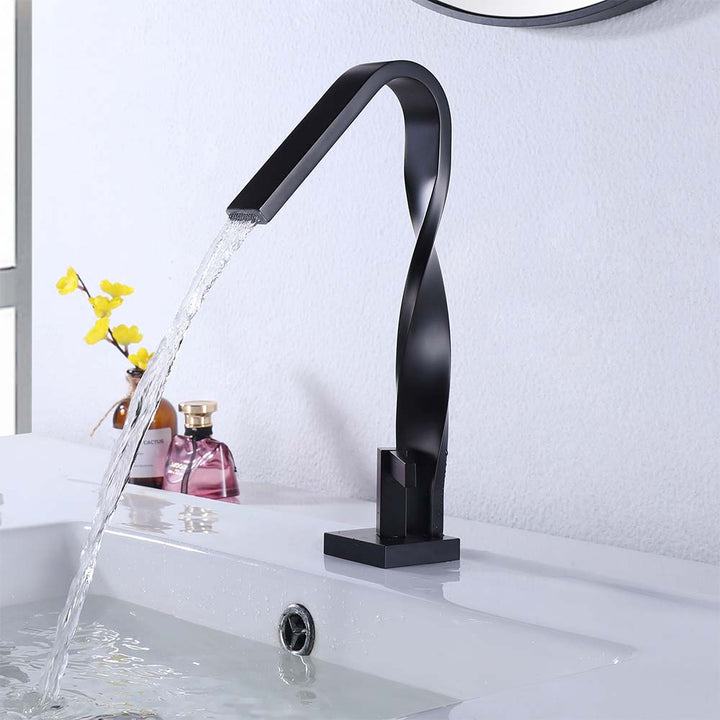 Modern twisted black faucet pouring water into sink basin