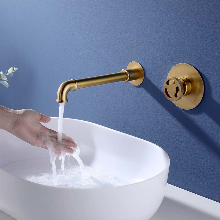 Gold wall mounted bathroom faucet running water into white basin